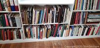 Bookshelf filled with assorted hardcover and paperback books arranged on three shelves.
