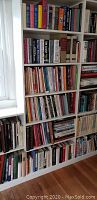 Shelf with multiple hardback books of various titles and colors arranged vertically and horizontally.