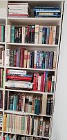 View of white bookshelves filled with a collection of hardback books in various colors and sizes