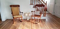 Two wooden rocking chairs and a floor lamp on hardwood floor near staircase and door.