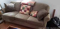 Front view of three-seat sofa with cushions and throw.