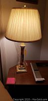 Vintage lamp with wood and brass base and cream pleated shade on desk