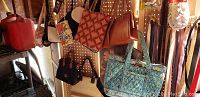 Photo showing part of peg board with assorted handbags including Vera Bradley bag, orange quilted bag, floral and black purses