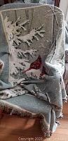 Winter scene throw featuring snow covered tree branches and red cardinals, folded over a chair