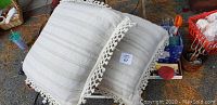 Two white/light grey striped floor pillows with fringe edges stacked on top of each other indoors.