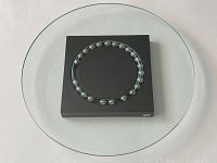 Top angle showing clear glass plate on black aluminum base with stainless steel balls.