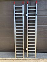 Photo showing two straight steel rung loading ramps approximately 72 inches in length placed vertically side by side against a garage door.