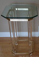Full view of octagonal glass top table with acrylic legs and gold-tone frame