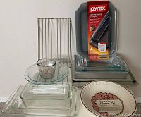 Photo showing entire assortment of glass Pyrex bakeware, metal cooling rack, measuring cup, strawberry glazed pie plate, and boxed non-stick baking pans.