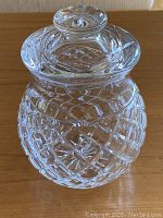 Full view of crystal glass jar with lid on, showing diamond cut pattern and rounded shape.