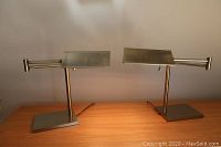 Pair of vintage brass desk lamps side by side on wooden surface.