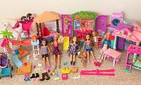 Overview photo showing six Barbie and Skipper dolls, multiple playsets, and accessories including a white rocking horse, sandbox, slide, stroller, and various shoes and bags.
