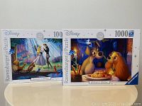 Photo of both Ravensburger puzzle boxes showing the Sleeping Beauty and Lady and the Tramp puzzles side by side on a plain surface.