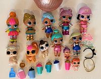 Photo showing assorted LOL Surprise dolls, baby dolls, pet figures, and multiple accessories laid out together on surface.
