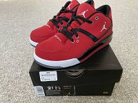 Pair of Jordan Flight 23 red and black youth basketball shoes sitting on their original black box. Visible white Jumpman logos on the tongue and sides.
