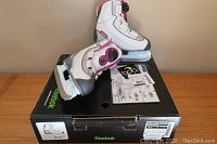 Pair of white and pink Reebok Boa girls ice skates resting on original black Reebok box with Boa branding and instruction sheet.