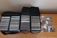 Three black Case Logic CD storage cases with assorted music CDs inside. Cases hold 30, 15, and 15 CDs respectively.