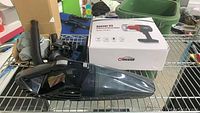 Holife handheld vacuum cleaner with black body and transparent dust container. Comes with charger and flexible hose, placed on metal shelf with Oasser box behind.