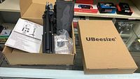 Box with folded tripod stands and UBeesize branded box, showing parts of ring lights.