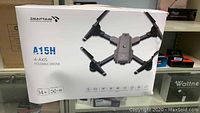 Box of Snaptain A15H foldable drone, showing branding, model info, and key features like 4-axis stabilization and voice control.