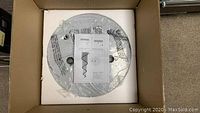 Photo of the packaged chrome flush mount base with instruction sheet on top inside box