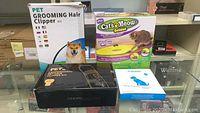 Lot shows four boxes: Pet Grooming Hair Clipper Kit box with dog image, Cats Meow Deluxe Cat Toy box, Bseen LED Dog Collar box, and an instruction manual.