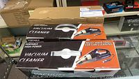 Two boxed portable high power vacuum cleaners for car cleaning with packaging showing product image and features.