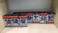 Nine boxed mini blue RC speed racing cars arranged on a shelf, boxes have black and orange design with clear plastic front.