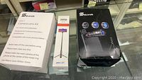 Photo of two white and black Selvim camera lens kit boxes and one tripod selfie stick box showing product packaging.