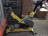 Side view showing the yellow frame, black seat, pedals, and flywheel cover with LaMond logo