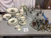 Full lot of Spode Christmas Tree dinnerware, assorted glassware, Nikko candy dish, brass reindeer candlesticks on table