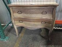 Photo of one wooden dresser with two drawers, curved front design, and metal ring handles