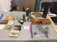 Wide view of lot showing matchstick holder, skull piggy bank, wooden boxes, brass ducks, various coasters and drinkware.