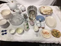 Overall lot view showing teapot, creamer, sugar bowl, cut-glass bowl, metal wine coasters, shell dish, assorted small bottles and bowls.