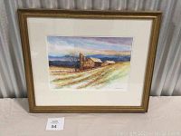 Full view of framed watercolor painting depicting a rural barn and field with trees and a colorful sky