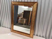 Front view of the rectangular mirror showing gold copper leaf print frame and reflective surface.