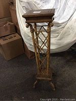 Photo showing the full tall scroll trellis metal and wood pedestal table with square wooden top, trellis column, and four-legged base.