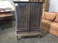 Front view of painted carved two-door armoire with floral vine motif.