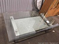 Full view of the coffee table showing the granite base, aluminum supports, and glass top above.