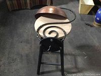 Front view of the lamp showing the copper dome shade and twisted metal stand on a small round wooden stool.
