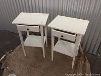Pair of white night stands shown side by side, each with drawer and lower shelf.