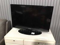 Front view of black Samsung 37-inch LCD TV on white table showing screen and base stand with price tag sticker.