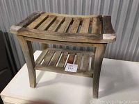 Front angle showing slatted teak wood shower bench with an additional lower shelf for storage.