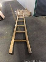 Full view of the bamboo ladder laid flat on floor, showing entire length and details of rungs and side rails.