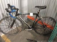 Full left side view of black Trek road bike with drop handlebars and blue tape.