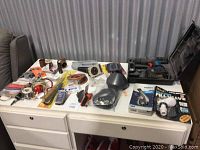 Overview photo of miscellaneous tools and hardware laid out on a white cabinet drawer from a distance.