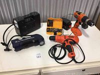 Photo showing all items in the lot including drills, inflator, drill bit set, battery and charger on white table