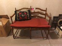Full front view of the wooden bench showing carved details, red seat cushion, and decorative rooster pillow.