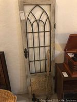 Full view of architectural wall art showing distressed wooden frame, metal windowpane design, decorative metal panel at bottom, with vintage metal towel ring attached.