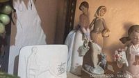 Photo showing two standing Lladro porcelain women figurines and a dog at the feet of one figure, set on a shelf.